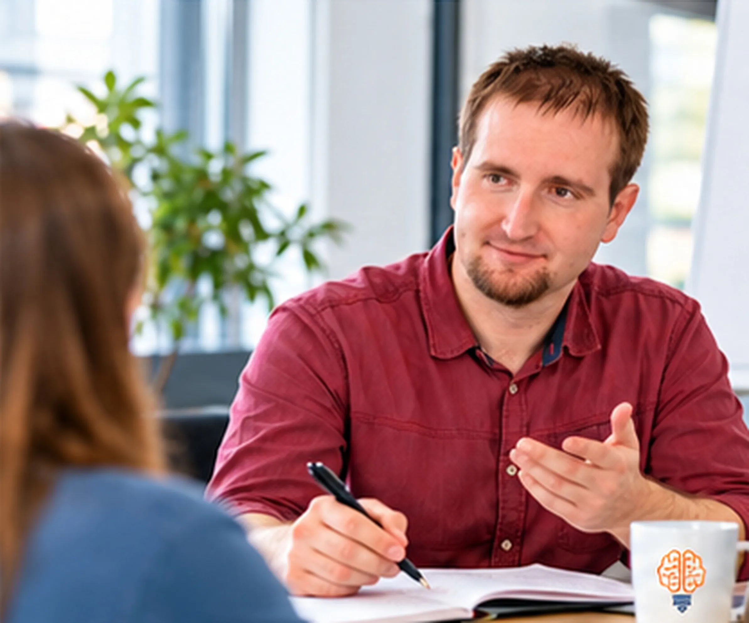 Stefan Ullmann erklärt im Gespräch am Tisch und macht sich Notizen